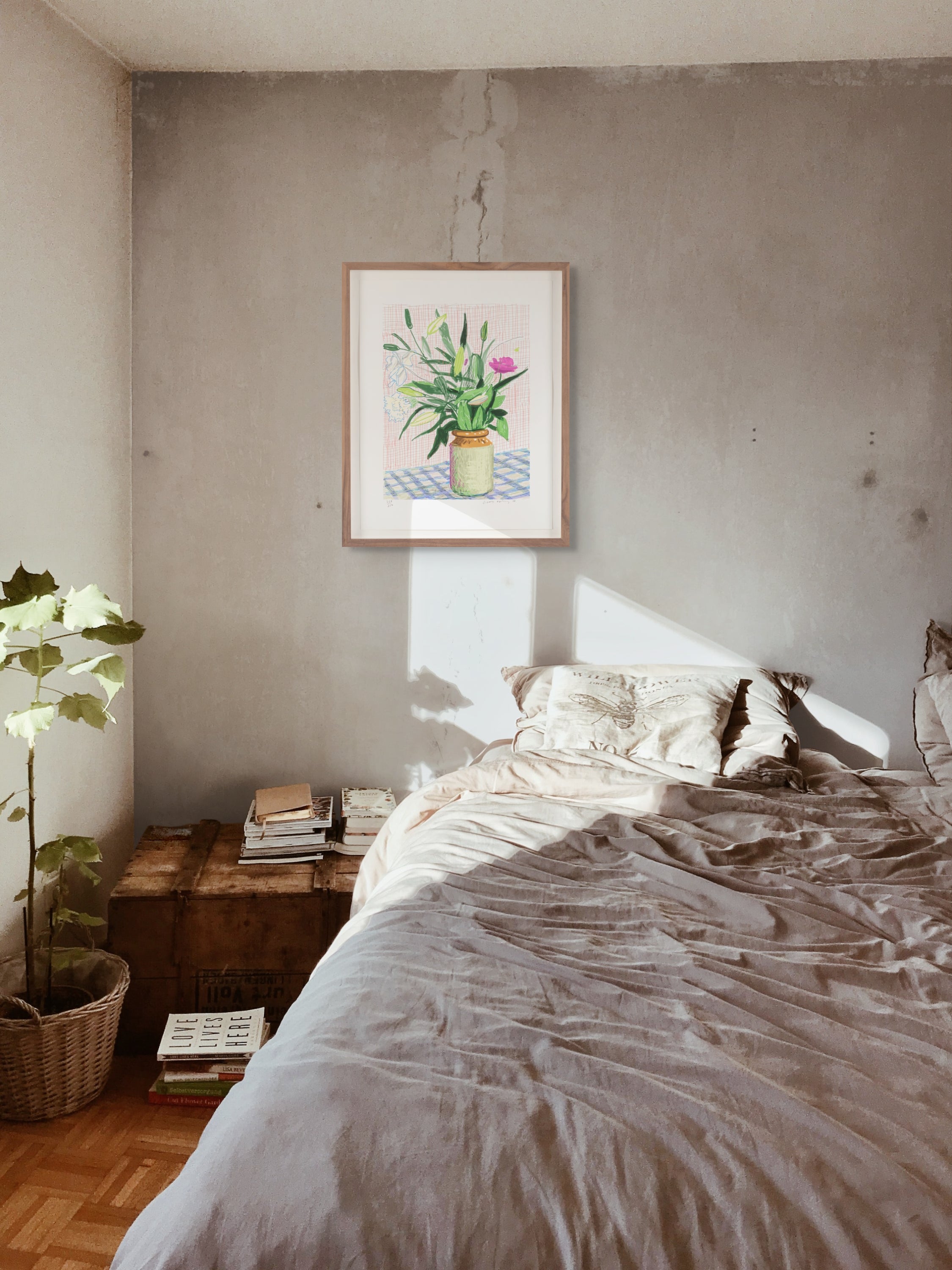 Bedroom with a bed, wooden nightstand, and framed david hockney ipad drawing flower artwork on the wall.