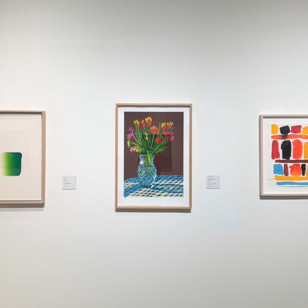 Art gallery with three framed artworks on a white wall inclkuding david hockney ipad drawing floral