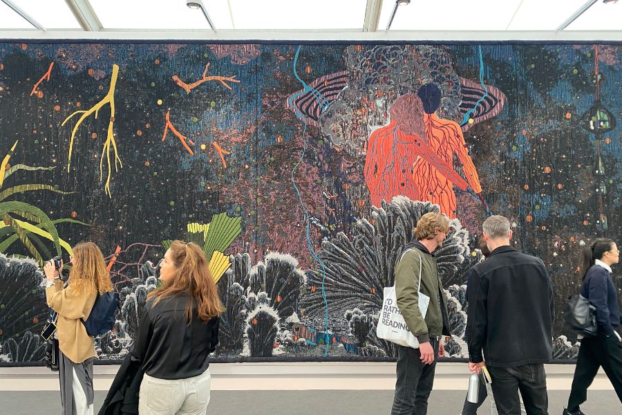 People walking past a large colorful mural in an urban setting at Frieze London Contemporary Art Fair