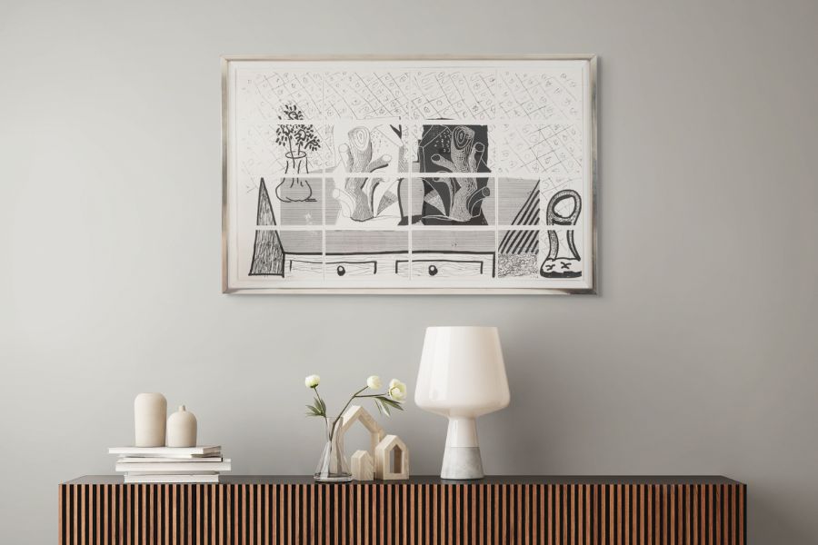 Framed black and white david hockney artwork on a wall above a wooden console table with decorative items.