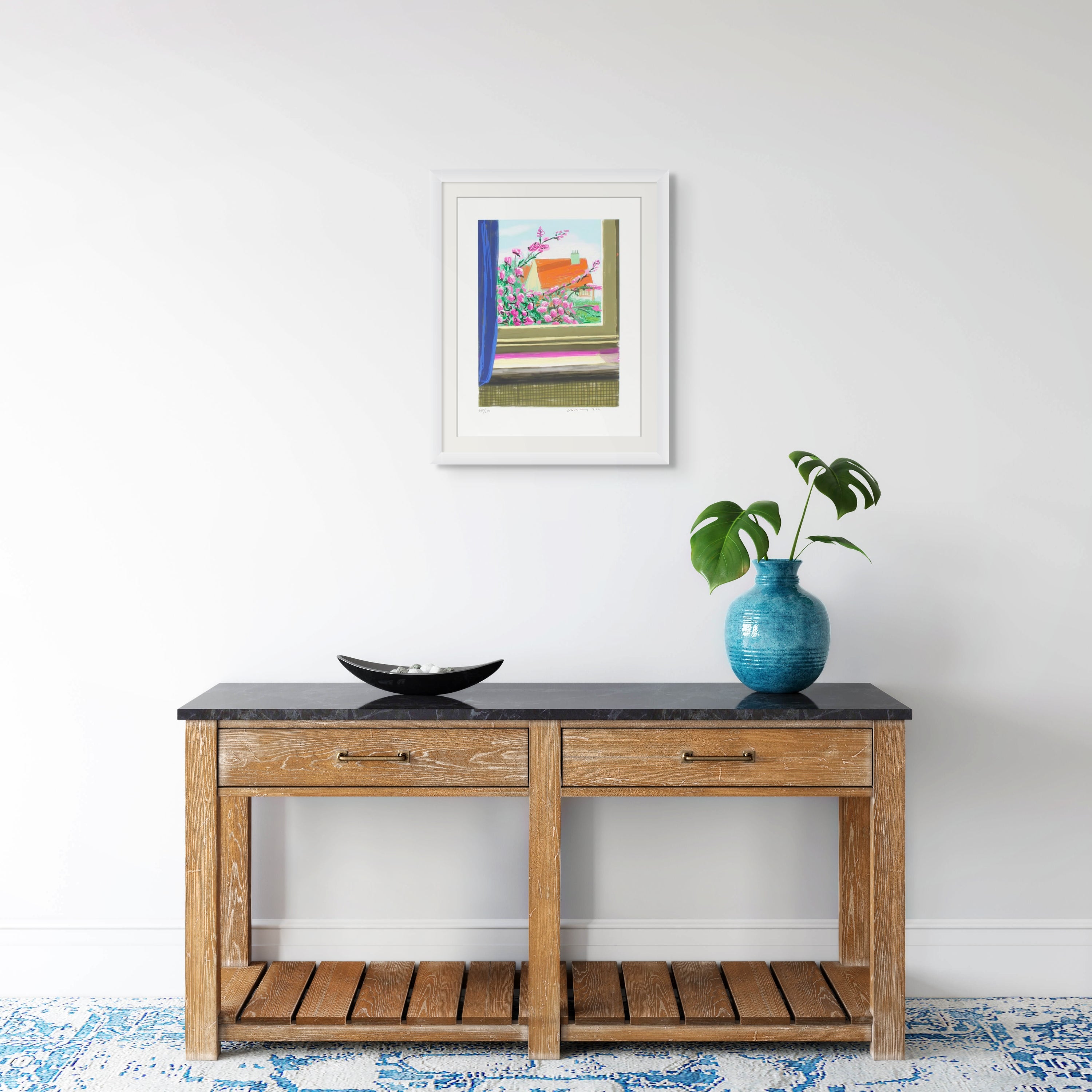 Wooden console table with a black top, featuring a vase and a framed david hockney ipad drawing  still life picture on a white wall.