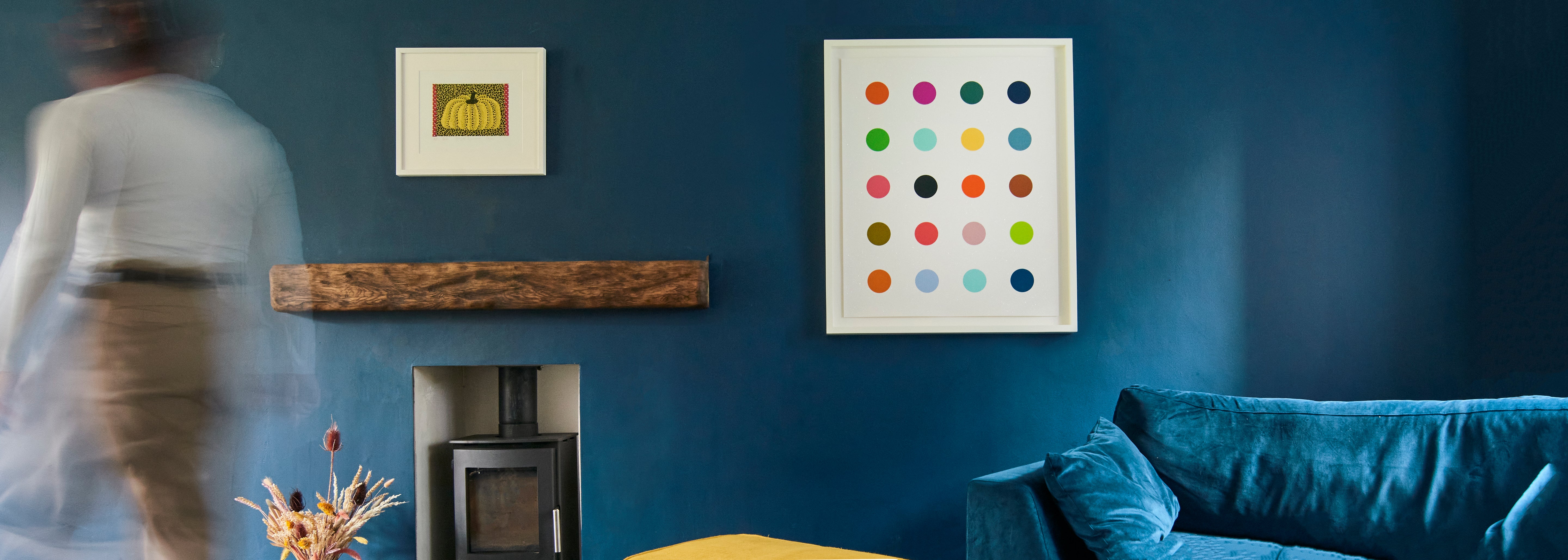 Living room with blue walls, a fireplace, and colorful dot artwork.