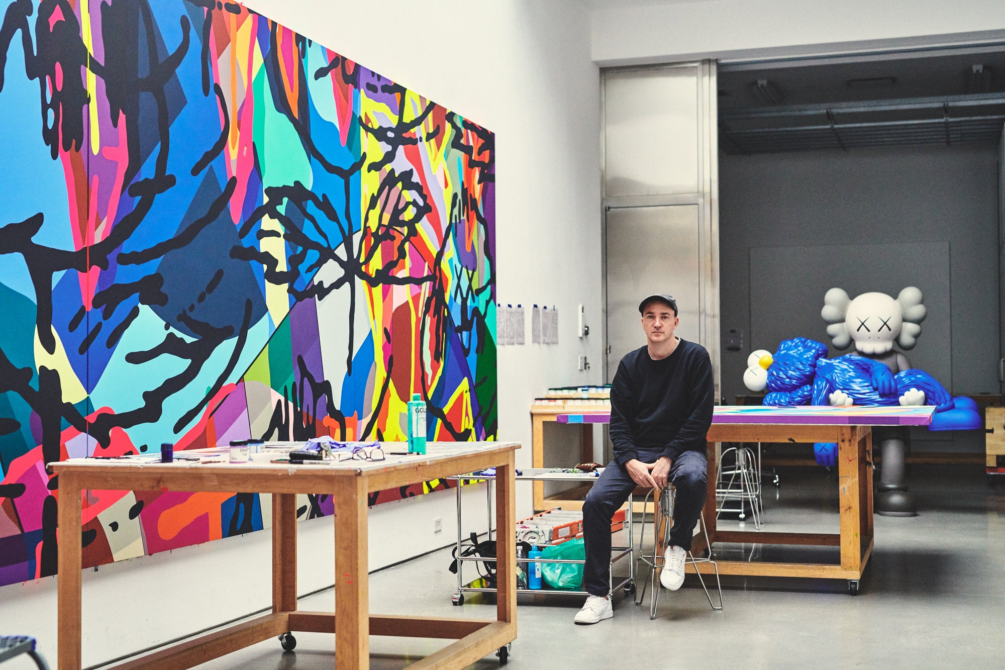 KAWS artist in his studio with paintings and sculpture